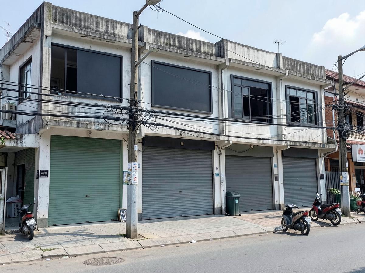 อาคารพาณิชย์ติดถนนสายหลักในเมืองต่างจังหวัด พร้อมป้ายร้านและรถจักรยานยนต์จอดเรียง